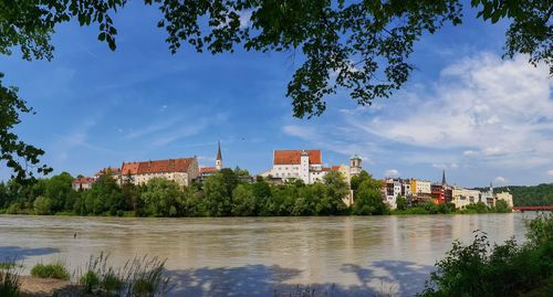Buildings by river against sky in city