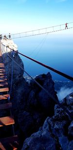 Bridge over rocks against sky during winter