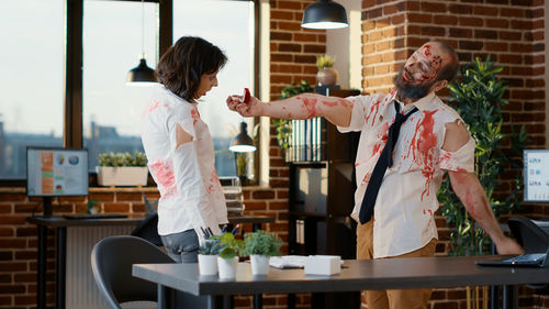 Businessman in zombie character giving engagement ring to colleague at office