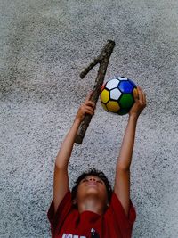 Portrait of boy playing with ball against wall