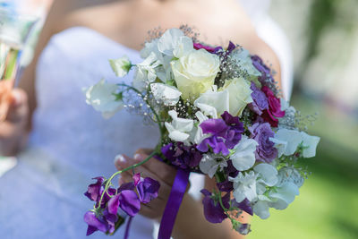 Midsection of bride holding flower bouquet at reception