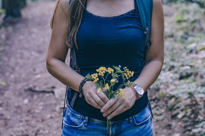 Midsection of woman holding bouquet in a forest