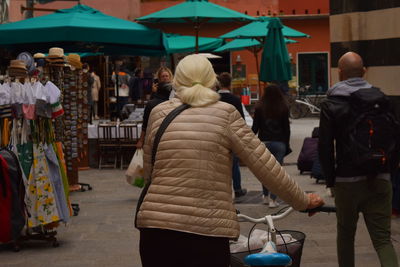 Rear view of people walking on street market