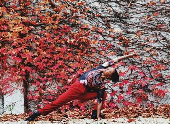 Full length of woman falling on red leaves during autumn