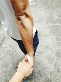 Midsection of man holding hand while standing outdoors