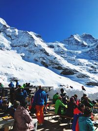 Rear view of people on snowcapped mountains against clear sky