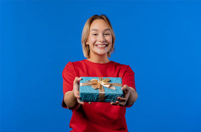 Portrait of young woman standing against clear blue background