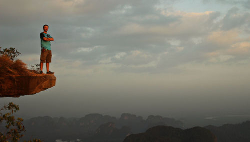 Full length of man standing at the edge of mountain against sky during sunset