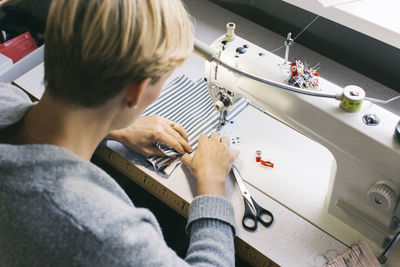 Woman using sewing machine on table in studio