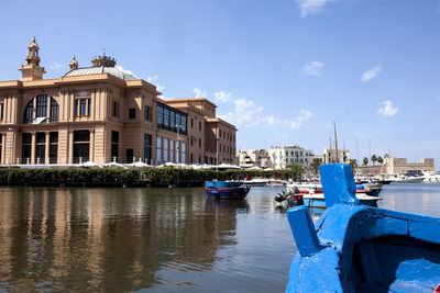 Boats moored on river by buildings in city against sky