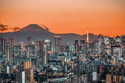 Illuminated buildings in city against sky during sunset