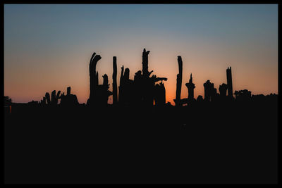 Silhouette people against orange sky during sunset