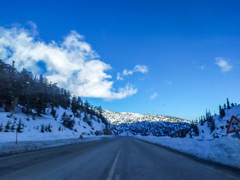 Road amidst snowcapped mountains against sky during winter