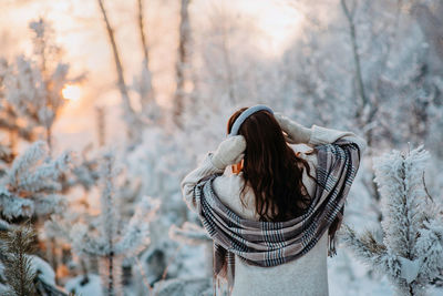 A girl in a beige fur coat is having fun in a fabulous snowy forest. stylish warm winter clothes. 