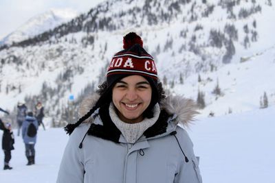 Portrait of smiling young woman standing on snow