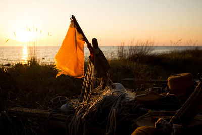 Close-up of flag at beach against sky during sunset