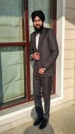 Portrait of young man standing against door