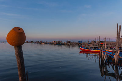 Scenic view of wooden post in sea against sky