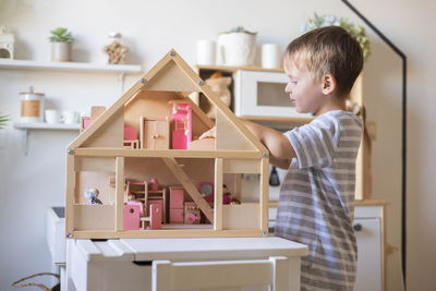 Side view of boy holding model house