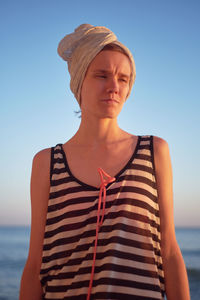 Young woman with head wrapped in towel standing at beach