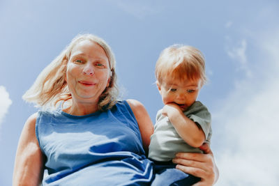 Portrait of woman with son standing against sky
