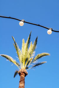 Low angle view of light bulb against clear blue sky