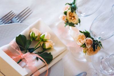 White doily on a plate decorated with ribbon and small roses in peach color wedding