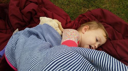 High angle view of toddler lying on blanket in yard