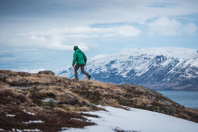 Rear view of man looking at snowcapped mountain against sky