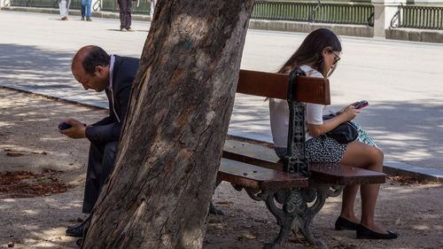 Full length of senior woman sitting on bench at park