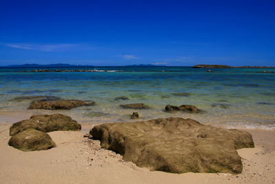 Rocks on beach against blue sky