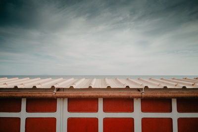 High section of house with sea in background against cloudy sky