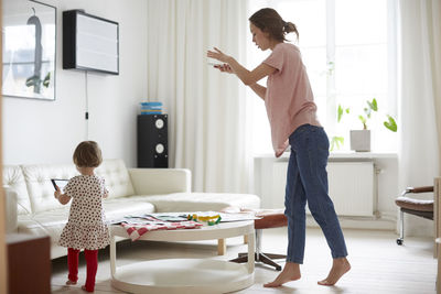 Fashion designer photographing fabric while daughter using digital tablet at home