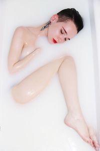 Young woman sitting on bed over white background