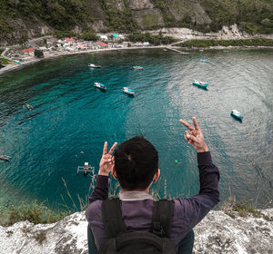 Rear view of man with arms raised in sea