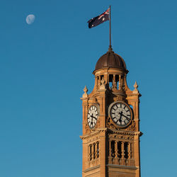 Low angle view of british flag on clock tower against blue sky