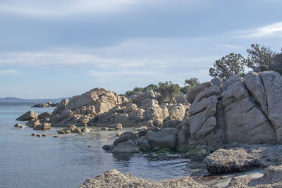 Rocks on shore by sea against sky