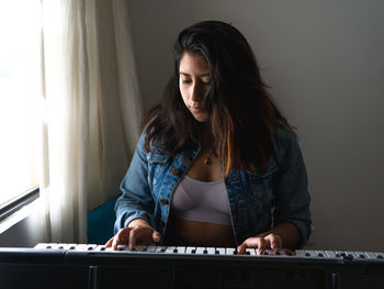 Young woman playing piano while sitting at home