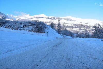 Snow covered landscape against blue sky