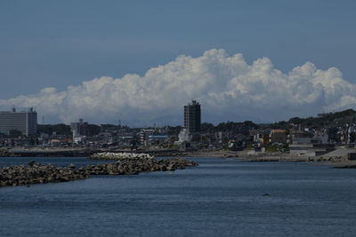 Sea by buildings against sky in city
