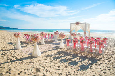 Deck chairs on beach against sky