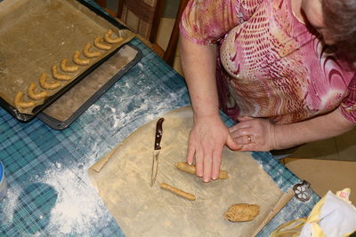 High angle view of senior woman preparing kipfel cookies in kitchen