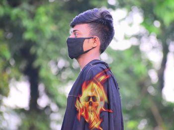 Boy wearing mask while standing by tree