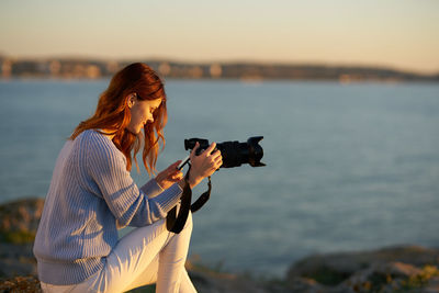 Midsection of woman photographing sea