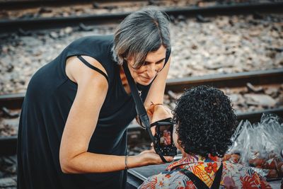 Midsection of woman holding camera while sitting outdoors