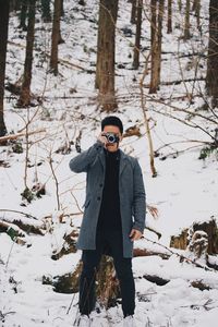 Man with camera standing on snow against trees