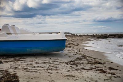 Boat moored on beach against sky