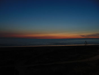 Scenic view of beach against clear sky during sunset