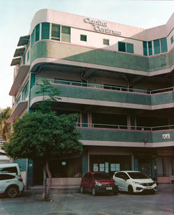 Cars on road by building in city against sky