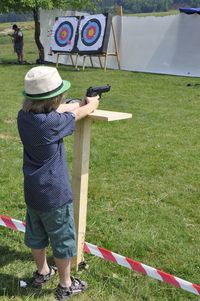 Rear view full length of boy shooting on grassy field